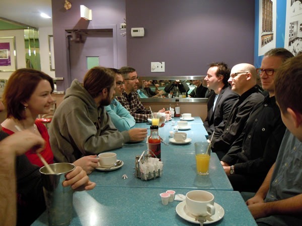 A long booth at Fran's diner, with assorted Toronto nerds drinking coffee and conversing