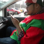Rannie Turingan in the passenger seat of the C-MAX checking his email on his phone