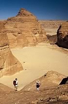 Two people walking in the desert.