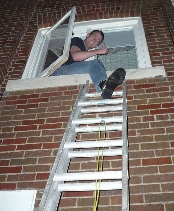 Dan on a ladder, entering the second-story window of his place via the window