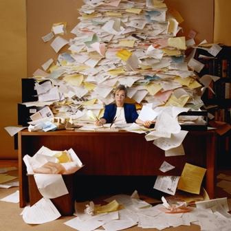 Woman at desk overwhelmed by a pile of paper