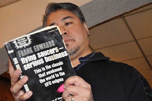 Joey devIlla reads a book titled "Flying Saucers - Serious Business"