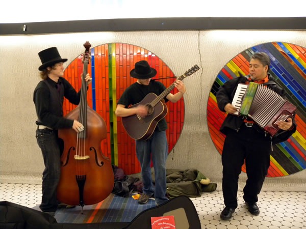 Joey deVilla playes accordion with an upright bass player and guitar player in Montreal Metro