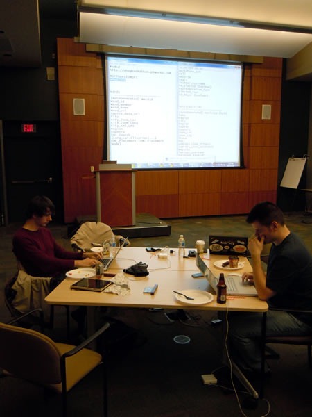 Two developers working on an open data problem, with a large project in the background
