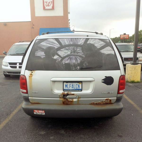 Rusty minivan with license plate "MLFALCON" and decal taking up rear window that displays Han and Chewie in the Millennium Falcon as the ship jumps to hyperspace.
