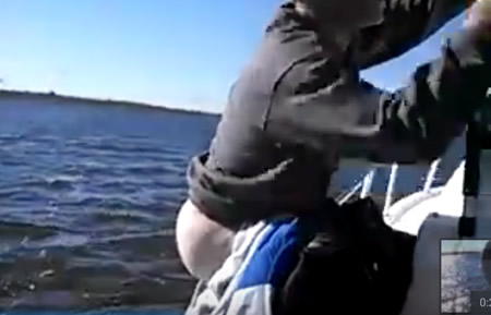 A man sticking his bare butt off the side of a boat, in preparation for pooping.