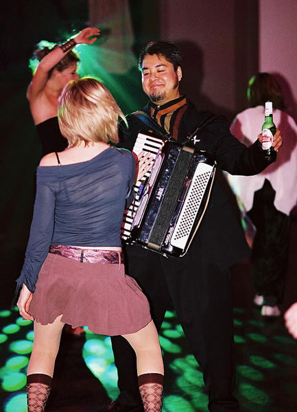 Joey deVilla, wearing his accordion, dancing with a lovely young lady.