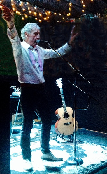 Gerry O’Kane onstage, standing with his hands in the air.
