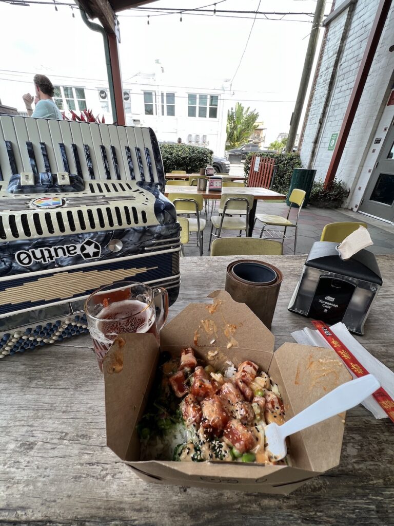 Photo: Poke bowl with beer and accordion in background.