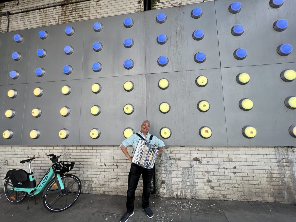 Joey deVilla poses with his blue accordion against the wall of the Southwark Street tunnel in London’s Southbank.