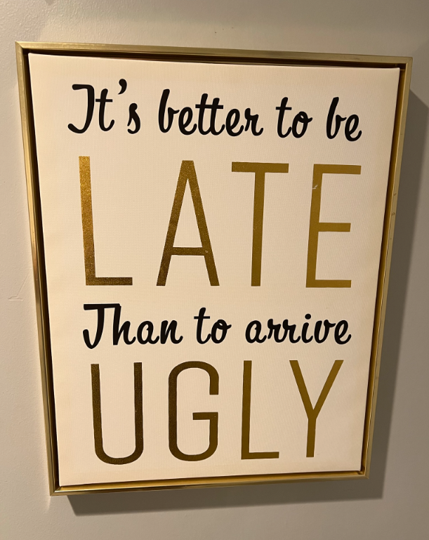 Frame sign on wall: “It’s better to be late than to arrive ugly.”