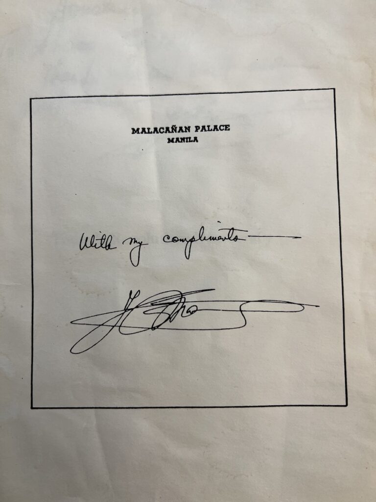 Inside page of the book, which has “Malacañan Palace, Manila” printed and a signature that reads “With my compliments,” and Ferdinand E. Marcos’ signature.