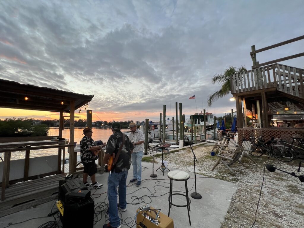 Jay, Dave, and Tom, the other members of the band setting up on our “stage” — the dock of Bayou Bistro, which opens up onto Tarpon Bay. A beautiful sunset in the background.