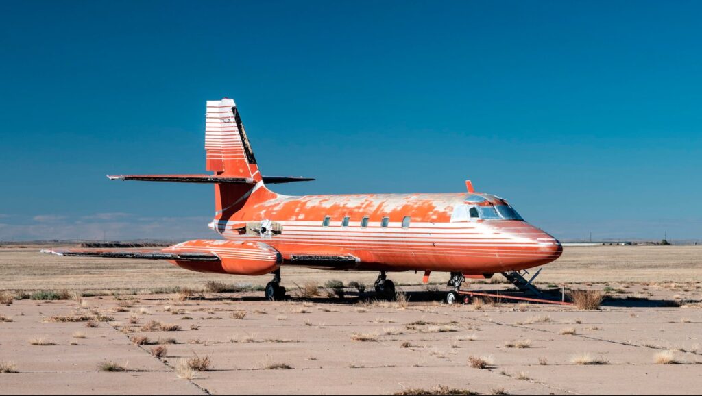 Exterior of the Jetstar for sale. It is red with silver stripes and is dilapidated.