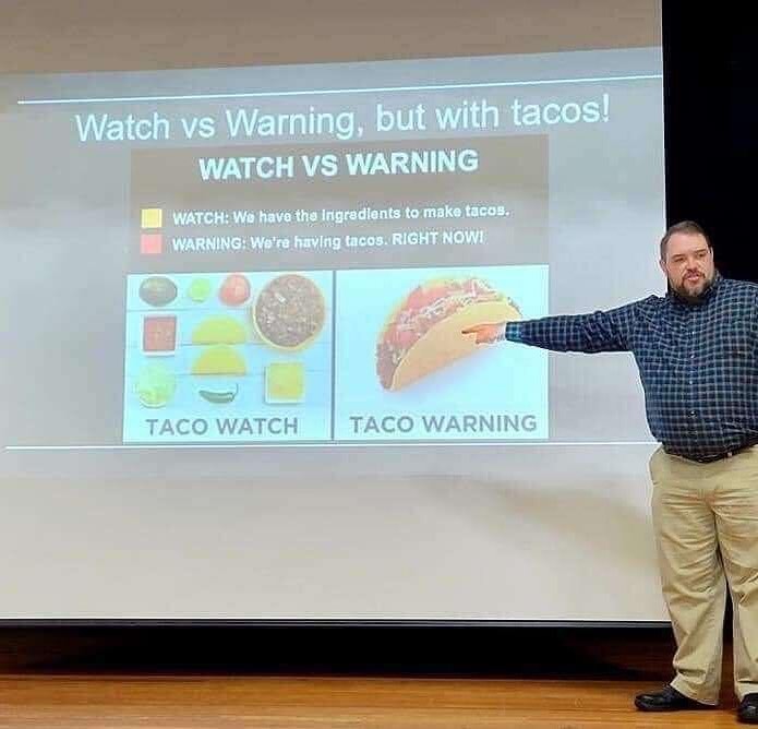Lecturer pointing to a slide explaining the difference between “watch” and “warning” using tacos. Watch means “we have the ingredients to make tacos,” while “warning” means “We’re having tacos. RIGHT NOW!” 